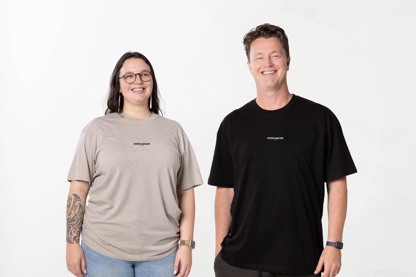 Two models smiling while wearing the HINT OF SARCASM T-shirt, a unisex Māori clothing piece made for Kiwis who love comfort and effortless style.